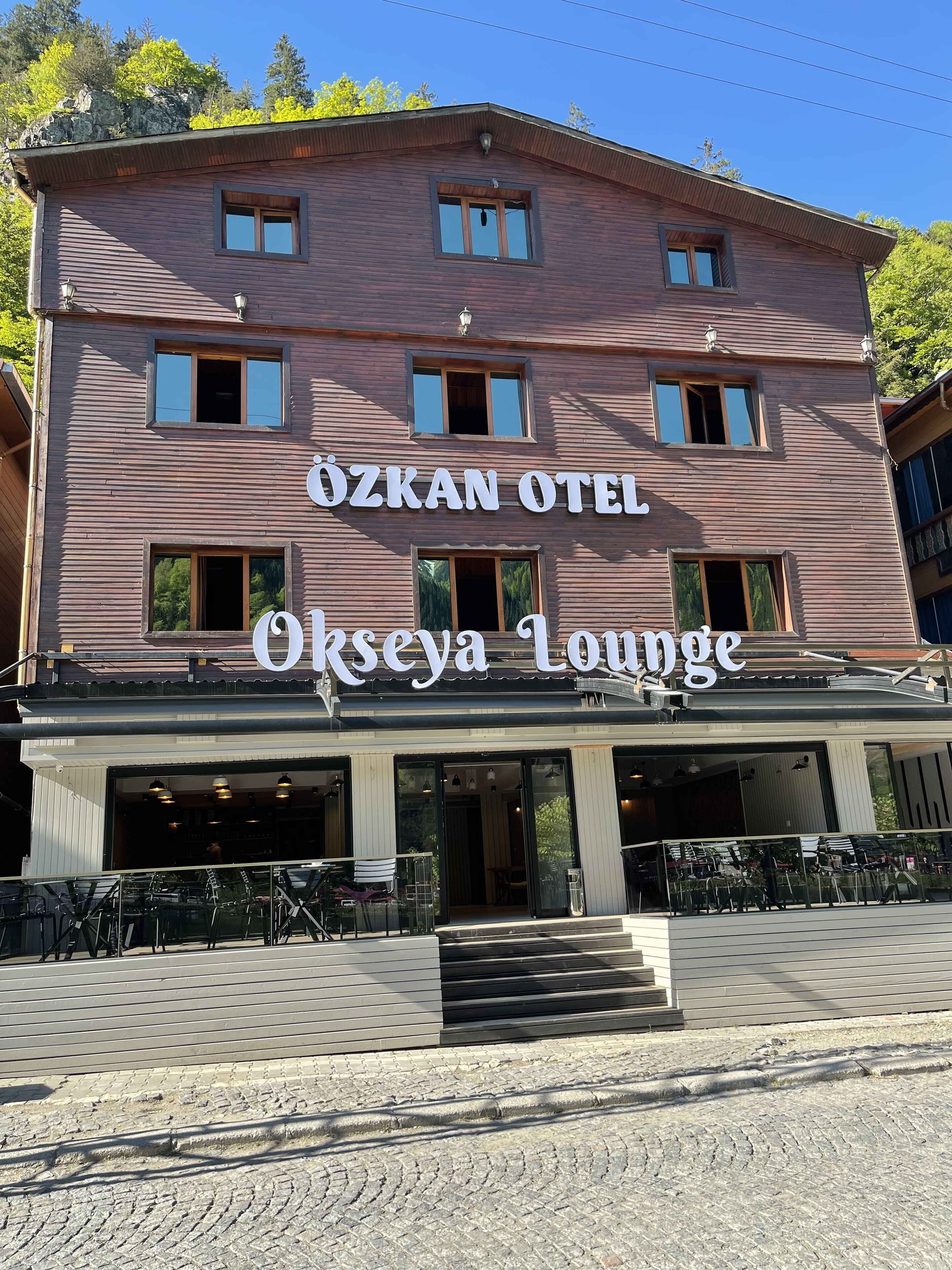 En byggnad med skyltarna "ÖZKAN OTEL" och "Okseya Lounge", vilket tyder på att det är ett hotell med en lounge.