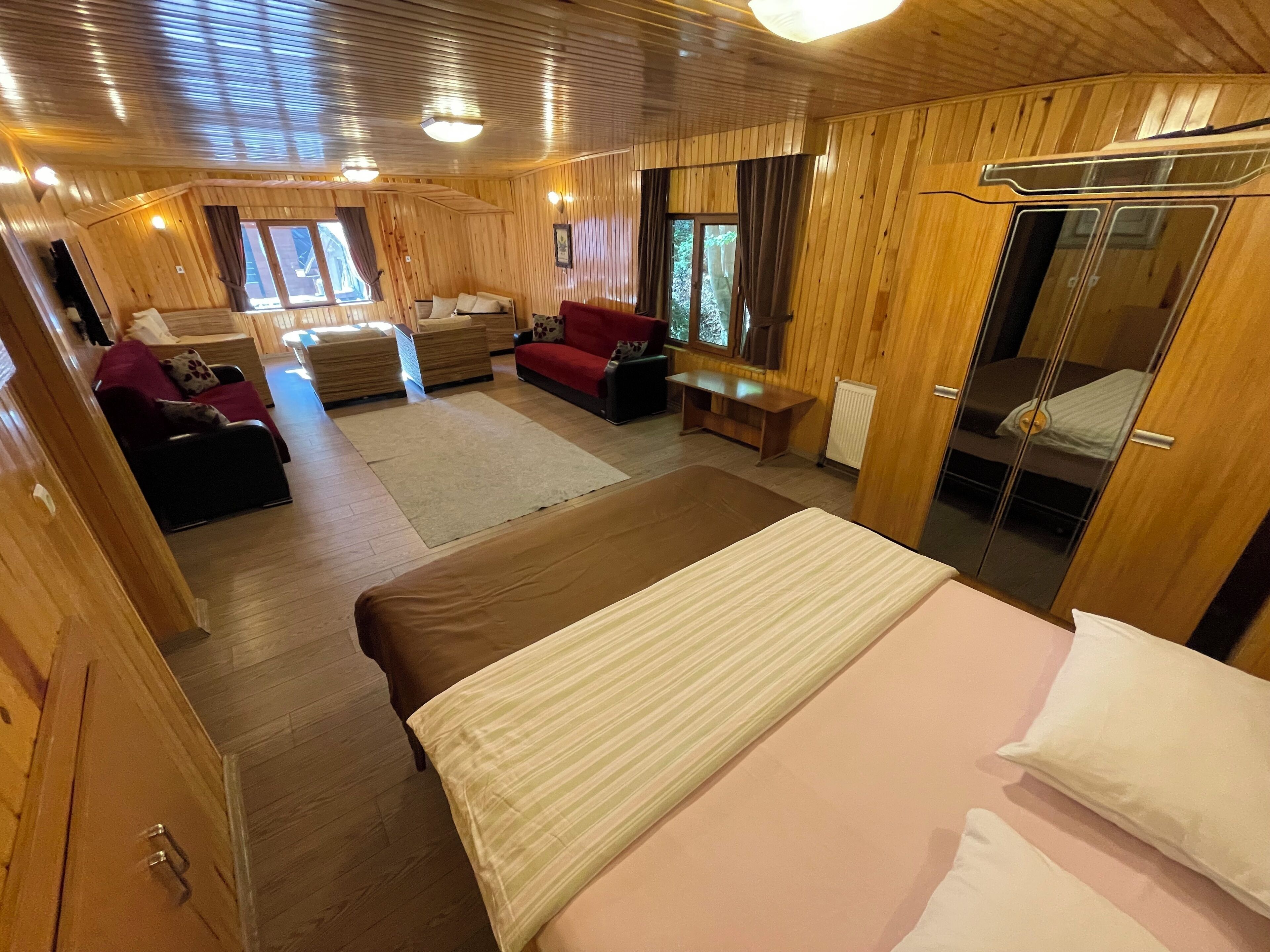 A wooden interior with a bed, a sofa, and a table.