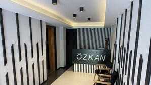 Un área de recepción moderna con un mostrador negro identificado como "ÖZKAN" y una silla de madera.