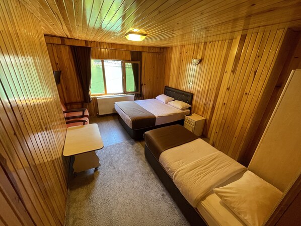 Una cabaña con dos camas, una mesita y una ventana con cortinas.