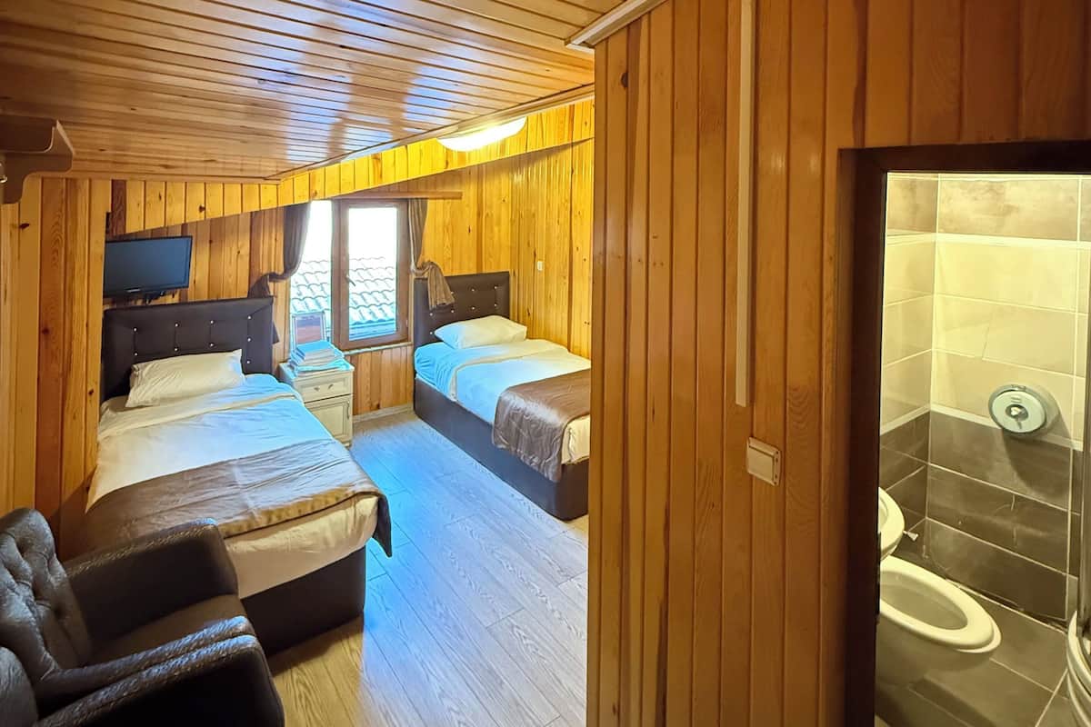 A wooden cabin with two bedrooms, a living area, and a bathroom.