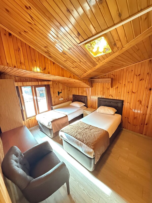 Una habitación tipo cabaña con dos camas, una silla y techo de madera.