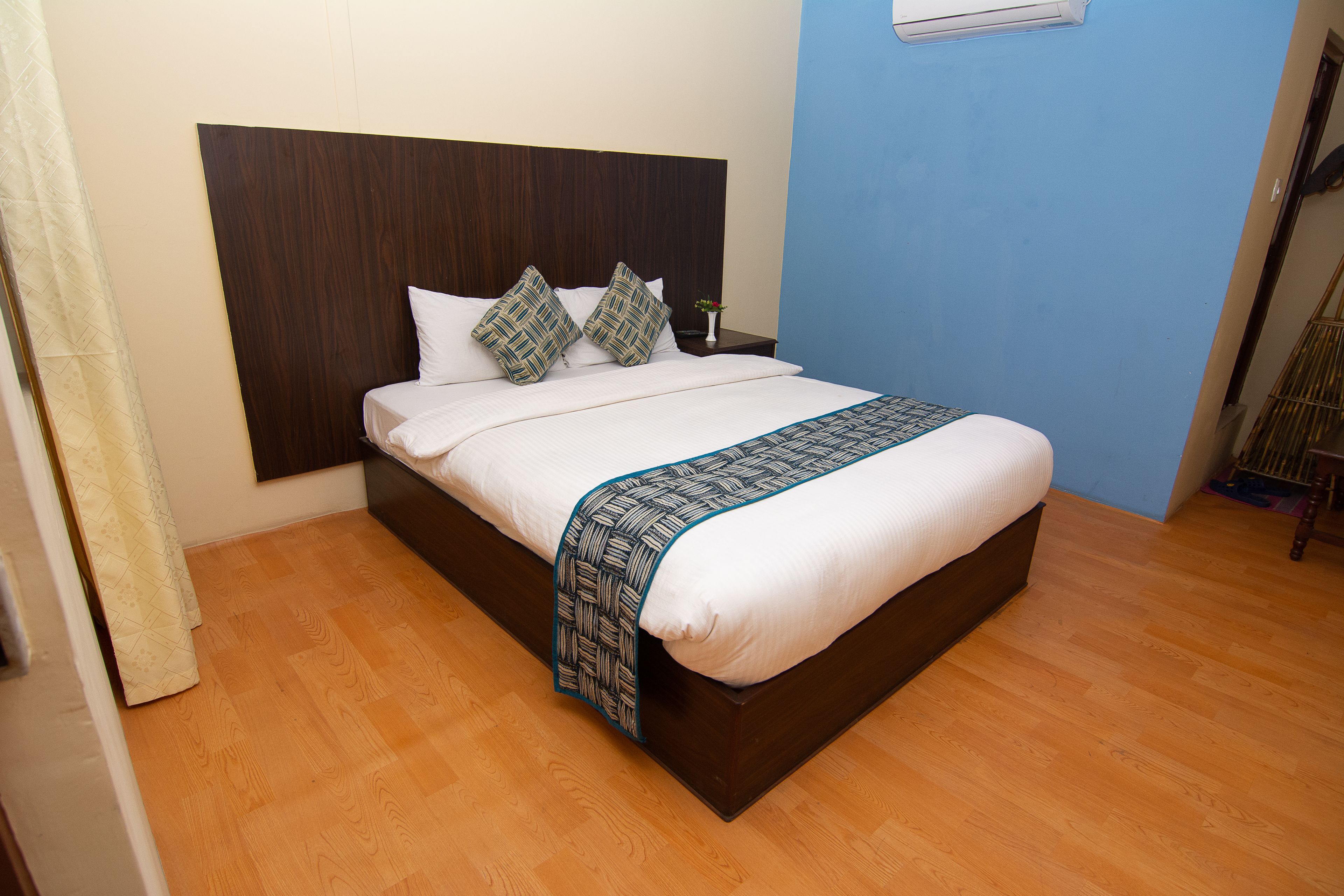 A neatly made bed with a dark headboard, a white comforter, and patterned pillows.