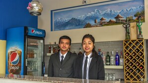 A reception area with a Pepsi refrigerator, a wine rack, and a painting of mountains. - Hotel Dine & Dream (Kathmandu)