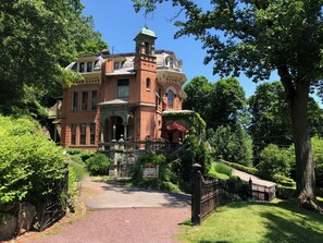 Ein großes, historisches Gebäude mit einem markanten Turm und einer überdachten Veranda.