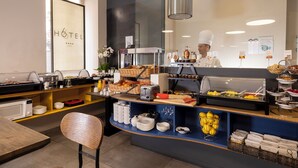 A breakfast buffet with various food items, a coffee machine, and a chef preparing food. - Hôtel 66 (Nice)