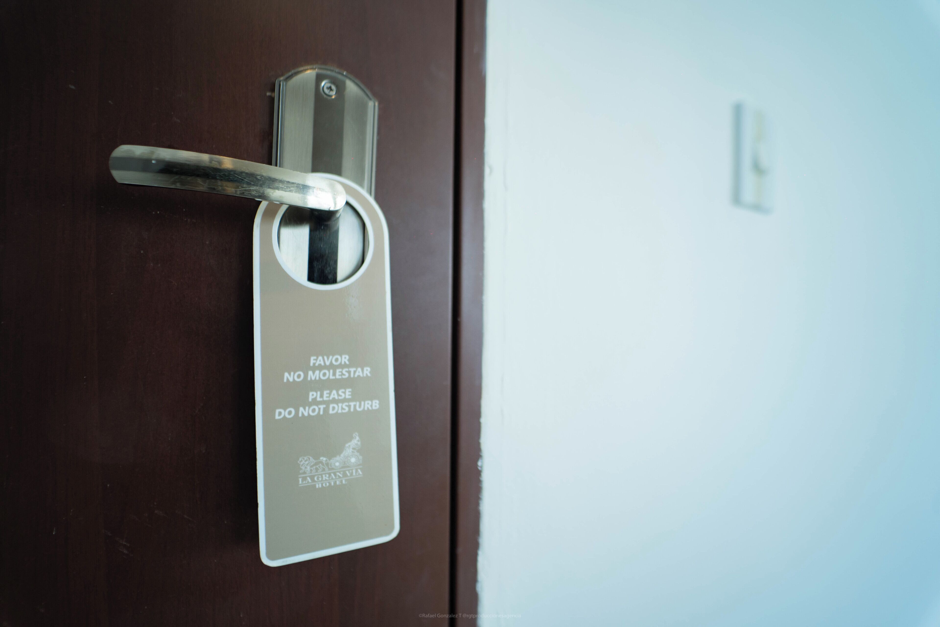 A door with a keyhole and a sign that reads 'FAVOR NO MOLESTAR PLEASE DO NOT DISTURB' and 'LA GRAN VIA HOTEL' below it.