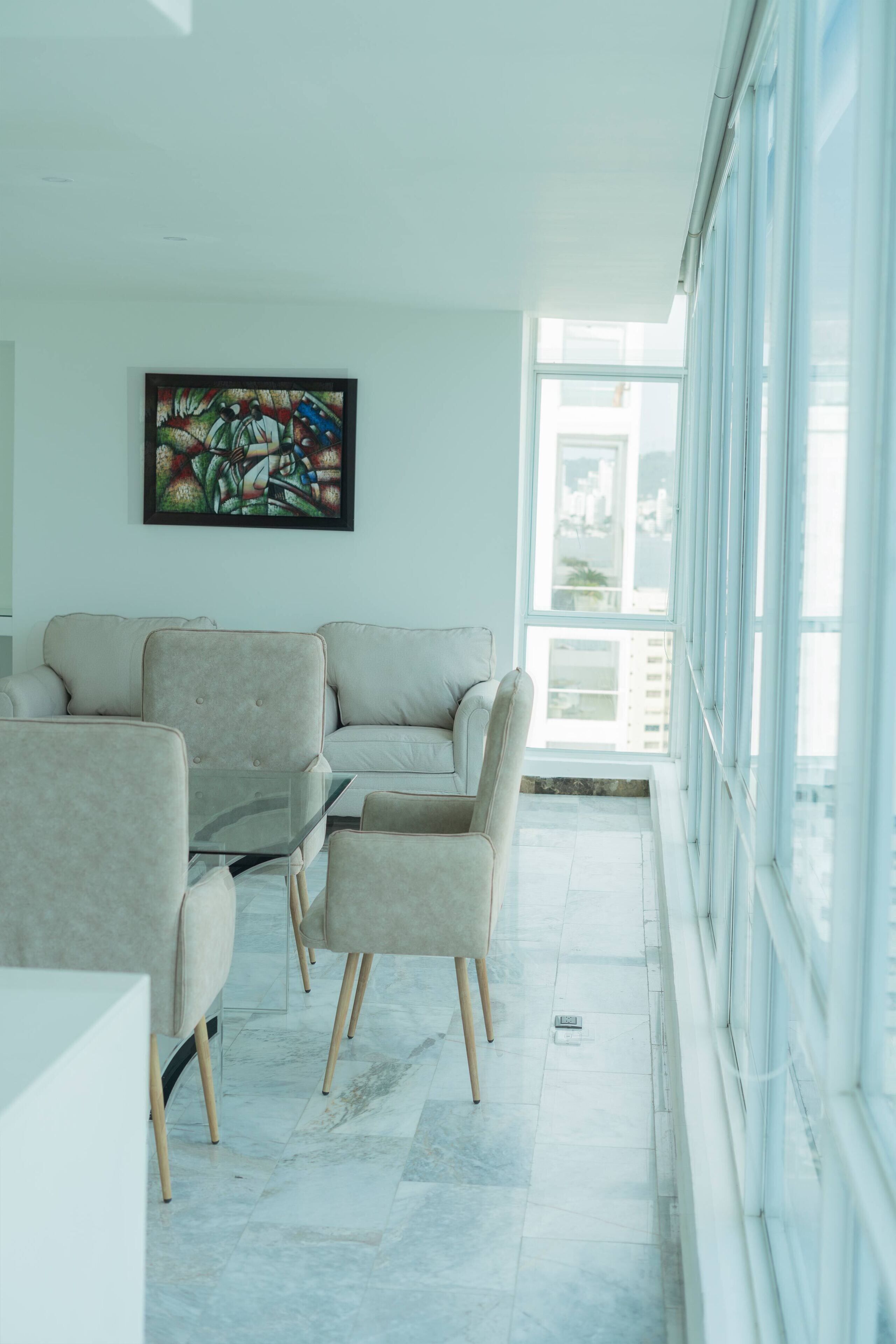 A modern living room with a sofa, chairs, and a glass coffee table.
