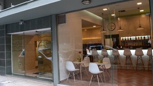 A modern cafe with a glass storefront, white chairs, and a bar area with bottles.
