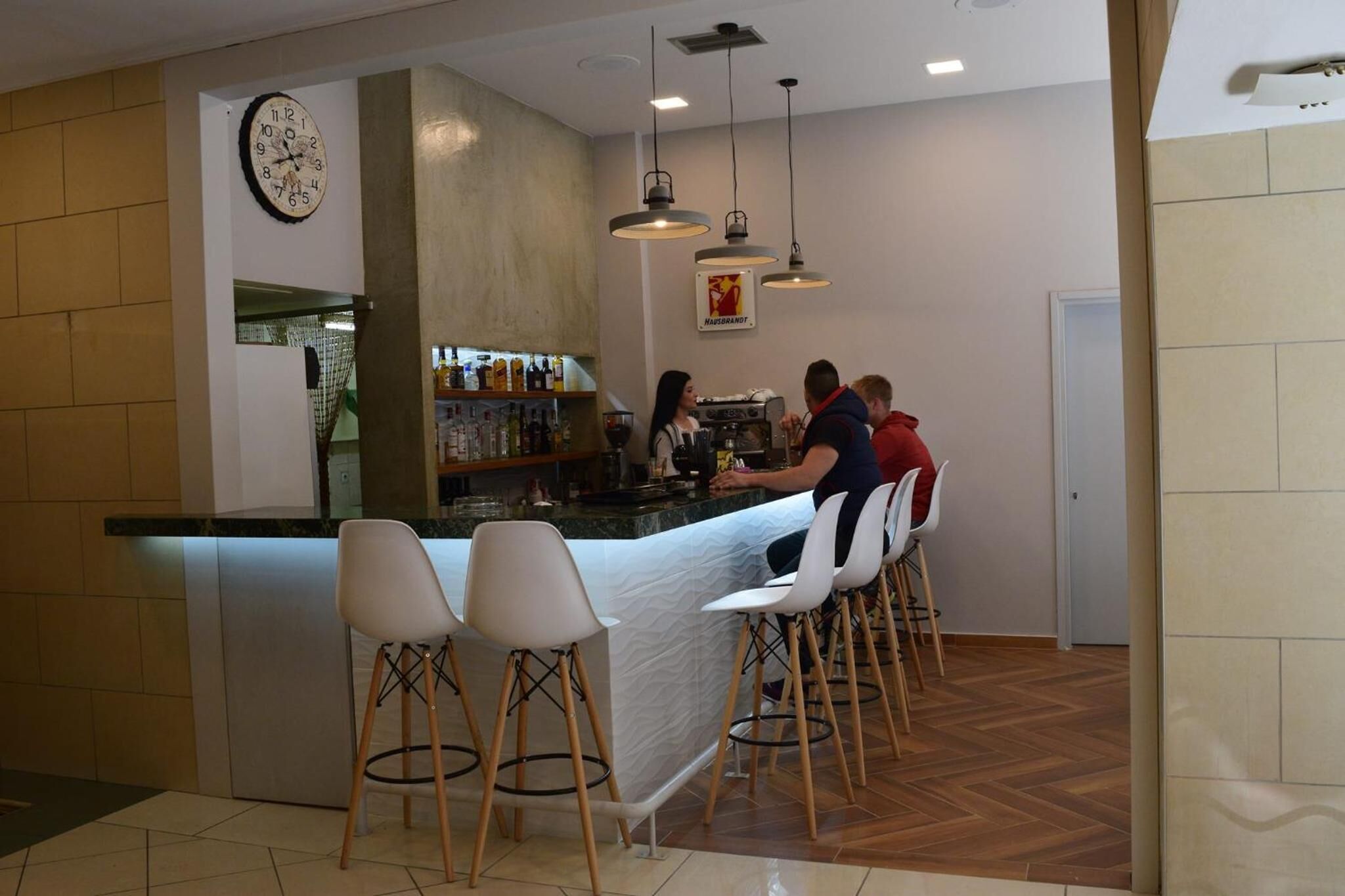 Una zona de bar con mostrador, taburetes y un reloj en la pared.