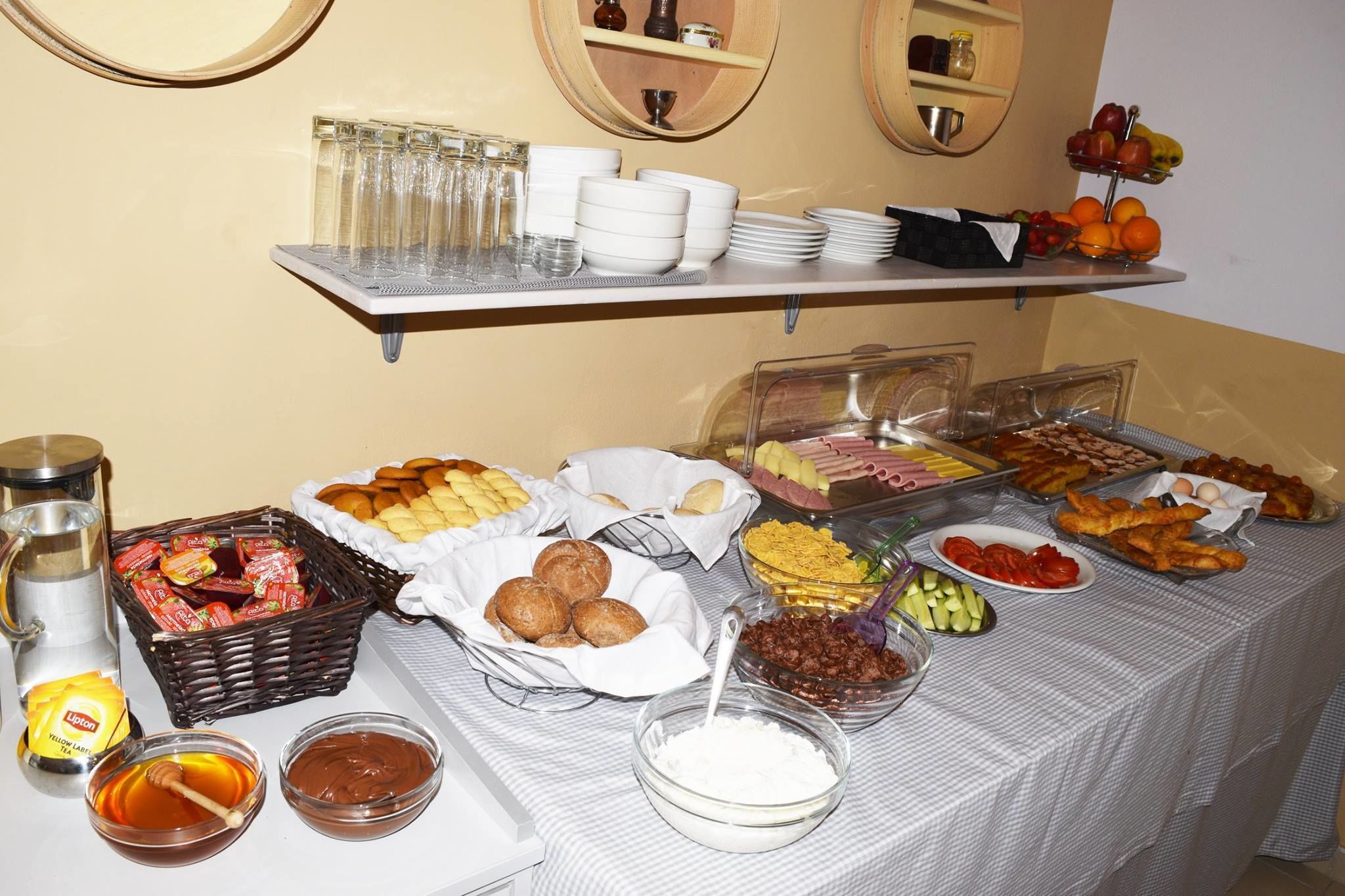 Una mesa de buffet con diversas opciones de comida, como frutas, pasteles y salsas.