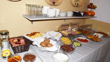 Una mesa de buffet con diversas opciones de comida, como frutas, pasteles y salsas.