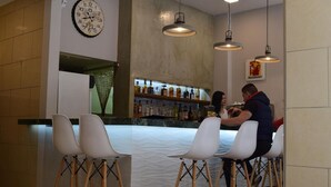 A bar area with a clock, bar stools, and a counter with bottles.