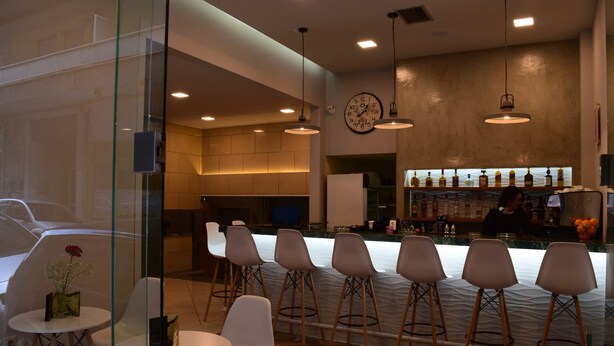 A modern bar area with a bar counter, several stools, and a clock on the wall.