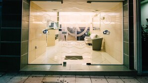A hotel entrance with a glass door, a reception desk, and a sign indicating free WiFi and internet access.