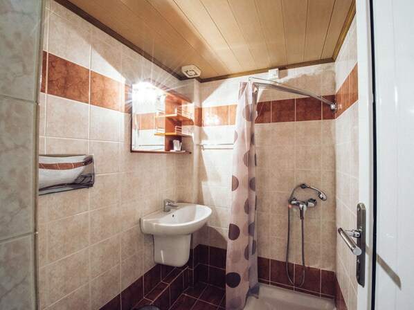 Un baño con lavamanos, ducha y perchero para toallas.