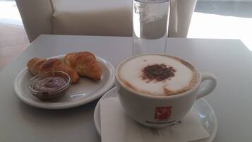A table with a cup of coffee, croissants, and a glass of water.