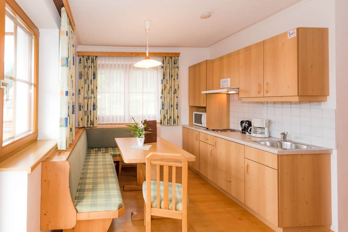 A compact kitchen with wooden cabinets, a microwave, and a sink.