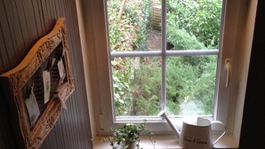 Een raam met uitzicht op een tuin, een houten wand met houtsnijwerk, en een witte deur.