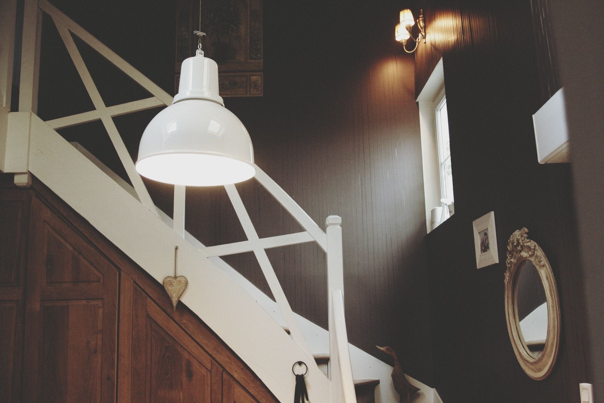 Un escalier avec une rampe blanche et une lampe blanche suspendue au plafond.