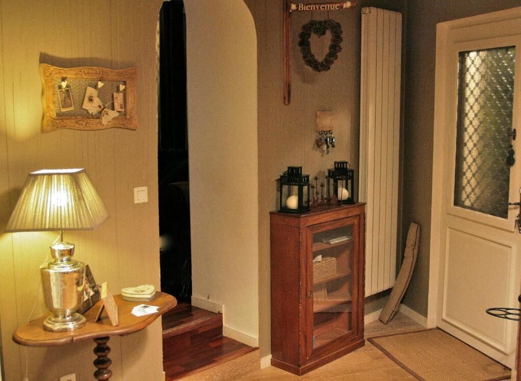 Un couloir avec une console en bois, une lampe, un tableau encadré, une pancarte de bienvenue et une porte dotée d’un panneau en verre dépoli.