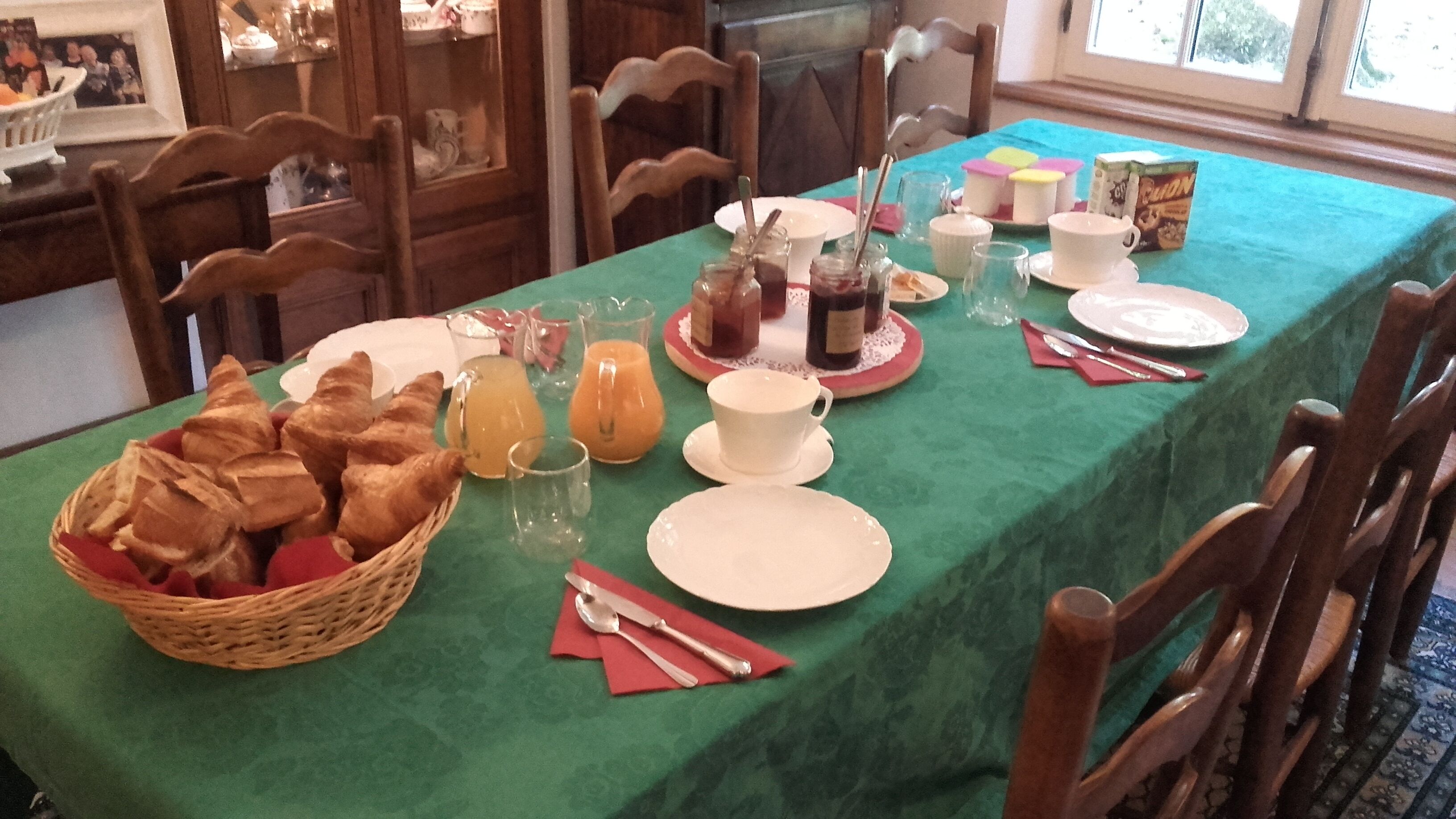 Une table à manger dressée avec des aliments pour le petit-déjeuner, notamment des croissants, du jus et du café.