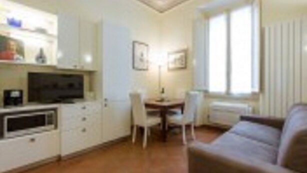 Un espacio habitable compacto con kitchenette, comedor y zona de estar.