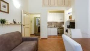 Un espacio habitable compacto con sofá, una mesa de comedor y zona de cocina.