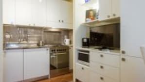 Una cocina compacta con alacenas blancas, horno empotrado y cafetera.