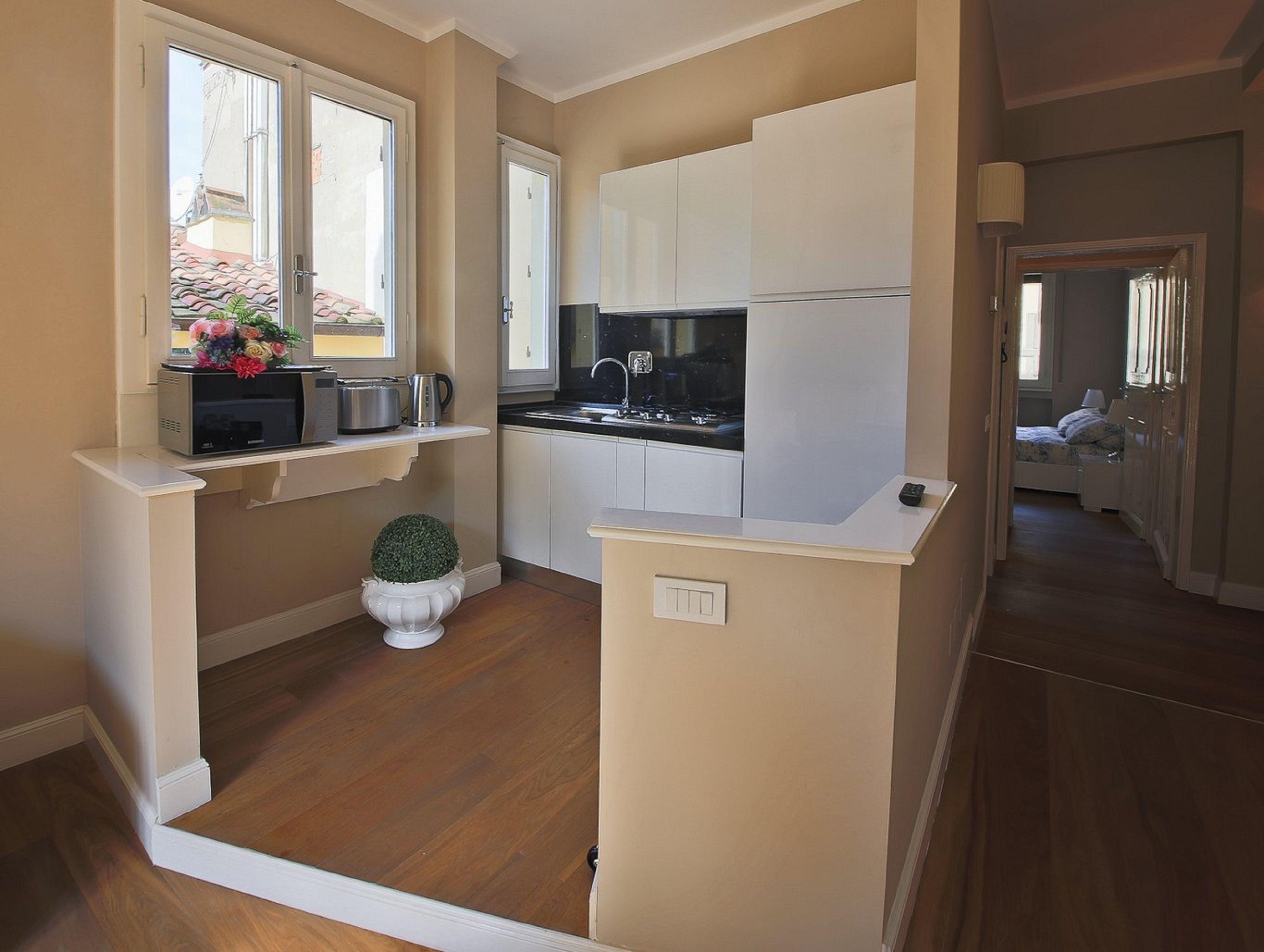 A compact kitchen with white cabinets, a microwave, and a small potted plant.