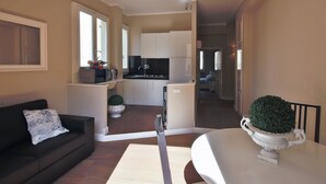 Un espace de vie compact comprenant un canapé, une table à manger et un coin cuisine.