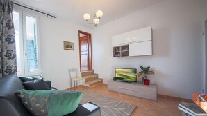 Un salon moderne avec un canapé, un téléviseur et un escalier menant à l’étage supérieur.