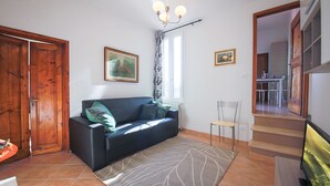 Un salon avec un canapé, un tapis, un téléviseur et un escalier menant à une autre pièce.