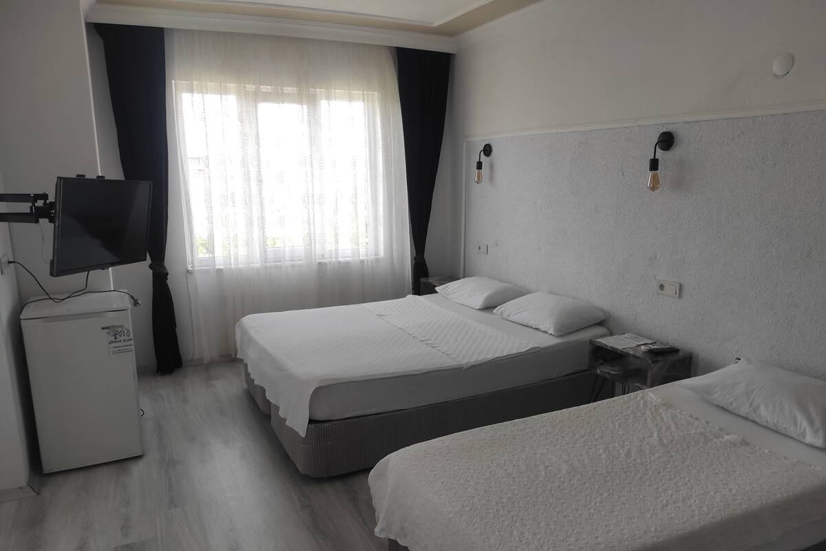 A hotel room with a bed, a desk, a television, and a small refrigerator.