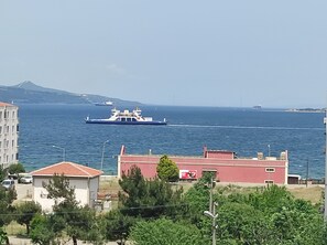 A coastal view with a ferry in the water, buildings in the foreground, and a distant mountain. - Bahceli Konak (Eceabat)