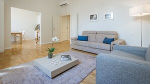Un salon moderne avec un canapé beige, un fauteuil bleu et une table basse agrémentée d’objets décoratifs.