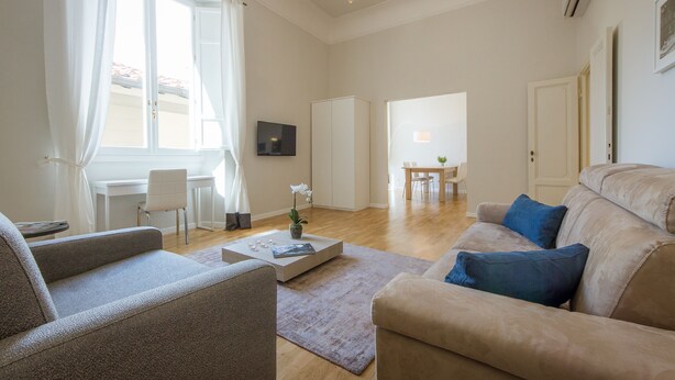 Un salon moderne comprenant un canapé, un fauteuil, une table basse et un coin repas avec une table et des chaises.