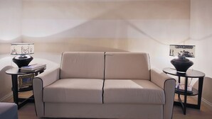 A neutral-colored sofa in a living room with two side tables, each with a lamp and a framed picture. A polka dot rug is on the floor. - Borgo dei Greci (Florence)
