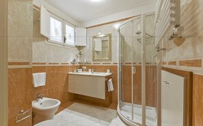 A bathroom with a shower, sink, and bidet.