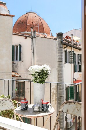 A balcony with a table, a vase with flowers, and two mugs with red handles. - Carlotta's Home (Florence)