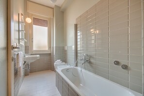 A modern bathroom with a large bathtub, a sink, and a toilet. - Carolina (Florence)