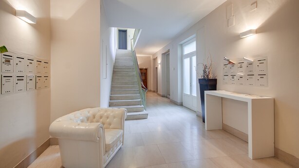 A modern hotel lobby with a staircase, a white sofa, and a reception desk.
