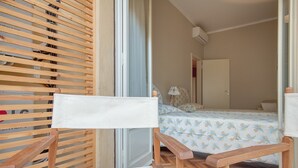 A wooden chair with a white cushion in a room with a bed and a door.