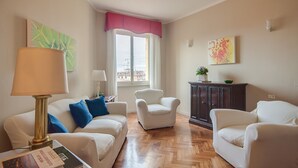 A living room with a sofa, two armchairs, a lamp, a cabinet, and a window with a view.