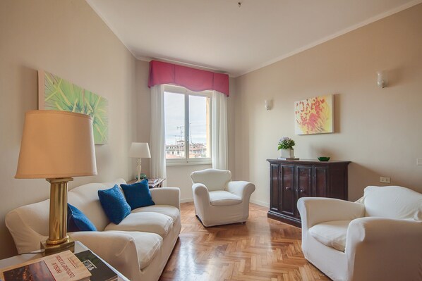 A living room with a sofa, two armchairs, a lamp, a cabinet, and a window with a view. - Carolina (Florence)