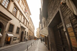 A narrow street with historic buildings, a visible street number '22', and a bus in the distance. - Carolina (Florence)