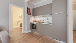 Una cocina moderna con armarios grises, horno empotrado y refrigerador de acero inoxidable.