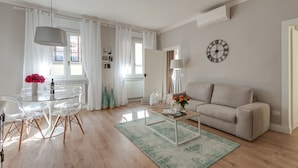 Una sala de estar moderna con una mesa de comedor de vidrio, un sofá color beige y una mesa de centro.
