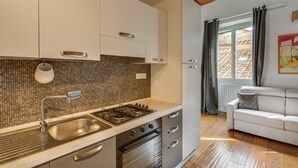 A modern kitchen with a tiled backsplash, stainless steel appliances, and a white countertop. - Federighi Loft (Florence)