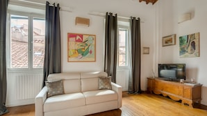 A living room with a white sofa, wooden cabinet, and a television. - Federighi Loft (Florence)